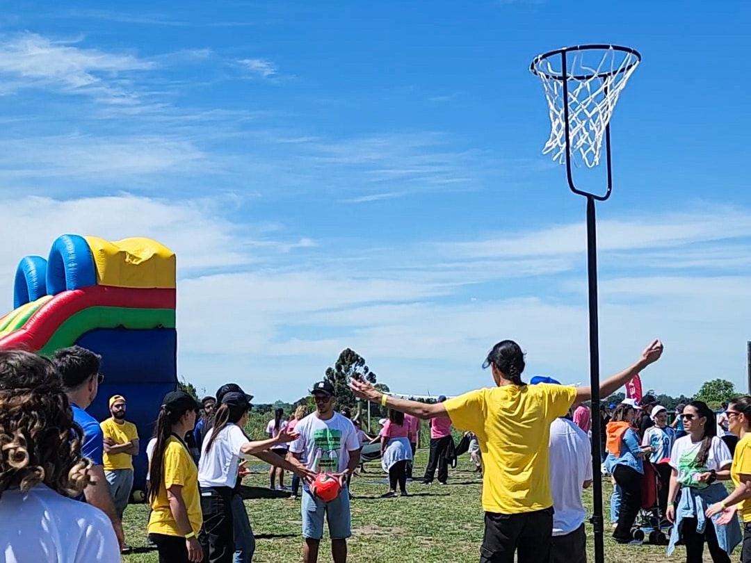 Un animador de remera amarilla dirige un juego con las familias, junto a un aro de básquet y un inflable