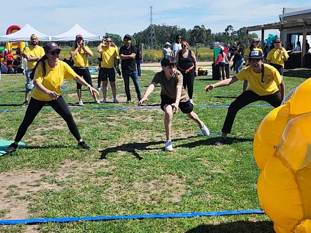 Participantes de remera amarilla compiten en una prueba de equipo sobre el pasto