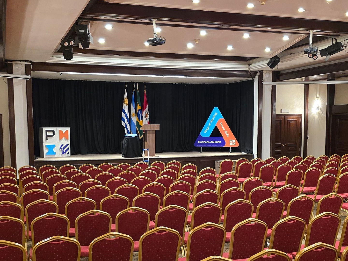 El salón del congreso preparado, con filas de sillas rojas y el escenario con las banderas