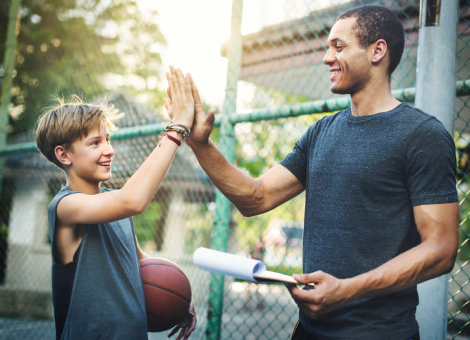 A coach giving a high five to a basketball player