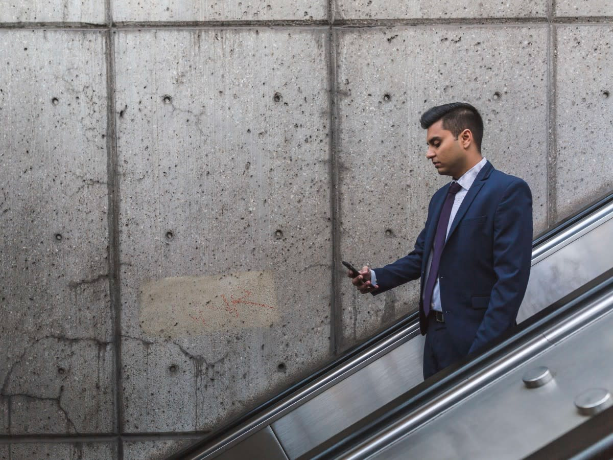 a business person looking at their cell phone on an escalator