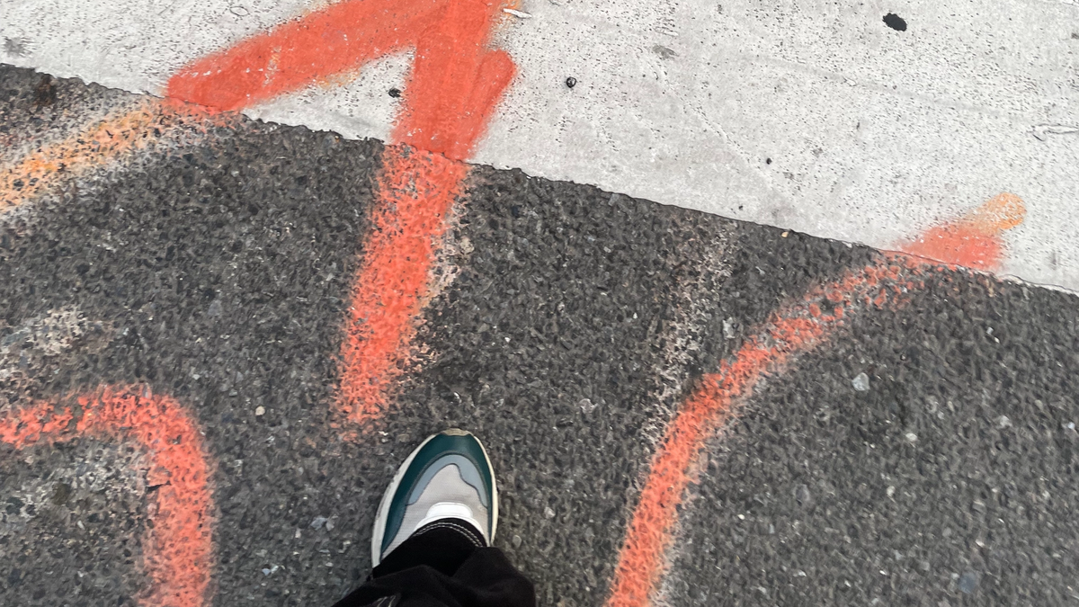 Orange spray paint in streets, which tells that communications cables are buried in the ground