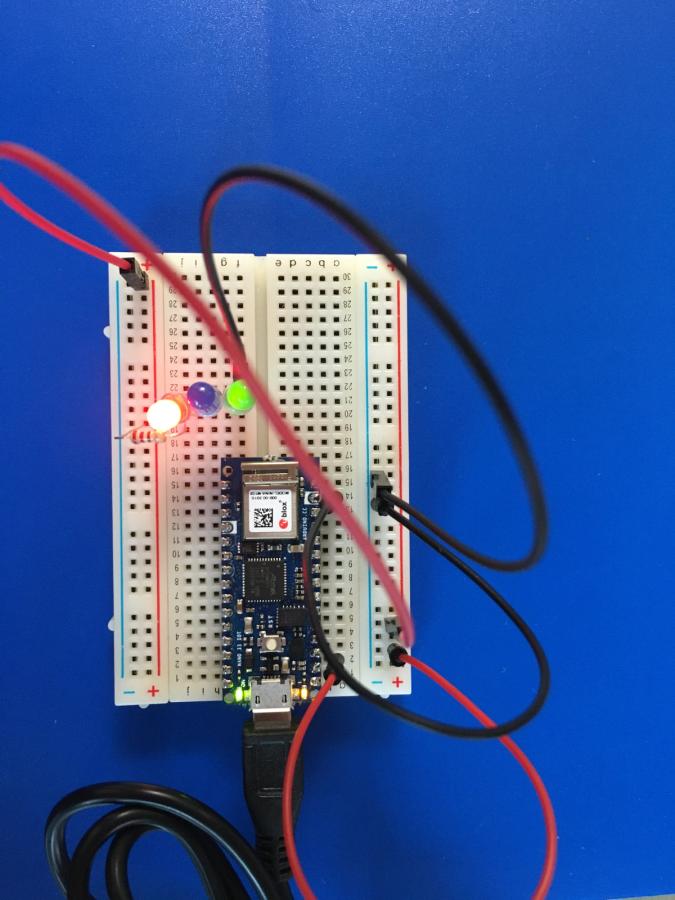 Photo of 3 LED lights on breadboard with circuits, only one light illuminating