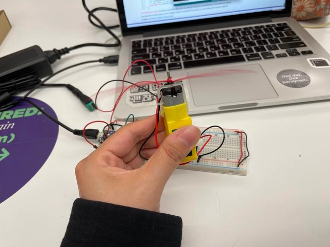 Photo of a spinning DC motor with a red piece of wire attached to it