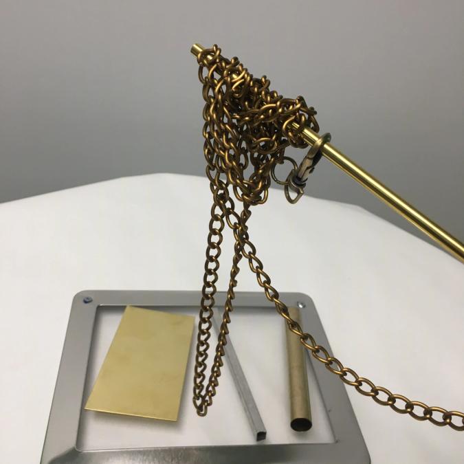 Photo of a metal stick with chains, on top of different sized metal scraps