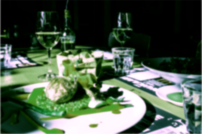 Image of a dining table with food plated, with a green glow
