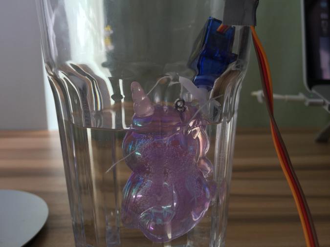 A purple resin unicorn attached to the servomotor with strings