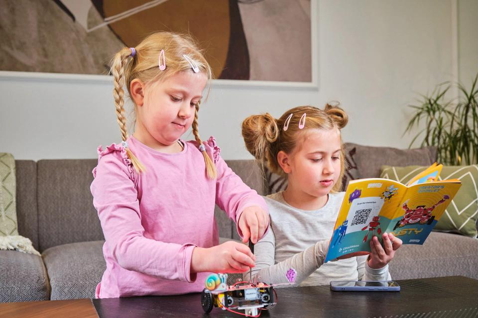 Two girls reading instructions and assembling CircuitMess Dusty