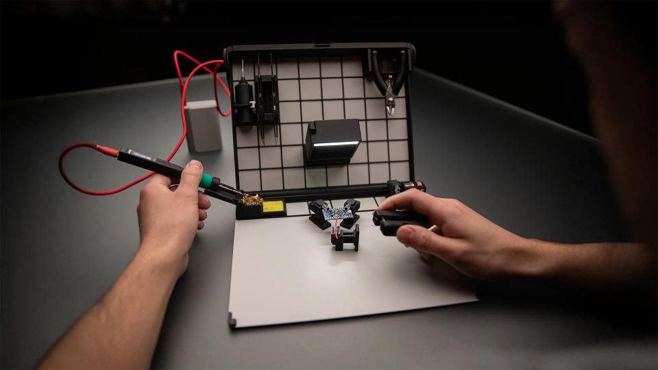 A person using SOLDR Deluxe soldering kit.