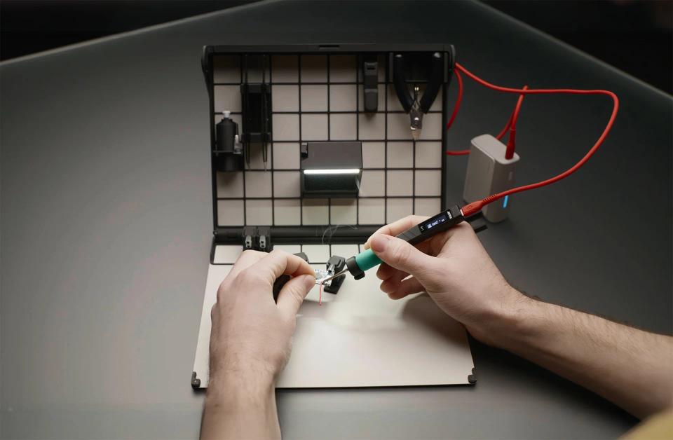 A person soldering with SOLDR Deluxe soldering kit.
