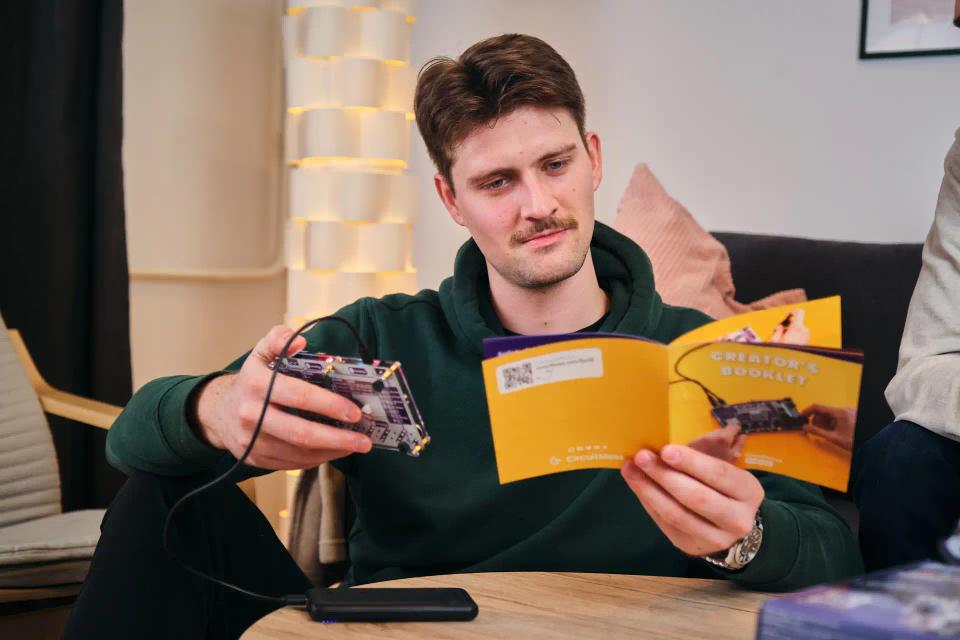 A man reading instruction and holding CircuitMess Synthia