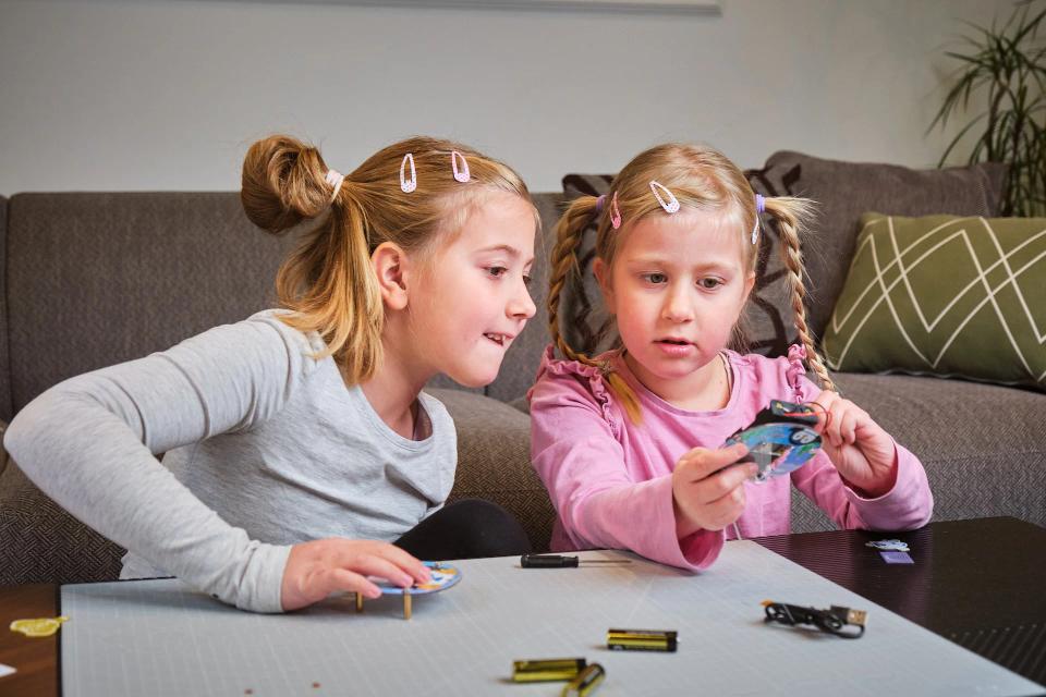 Two girls putting batteries into their CircuitMess Codees
