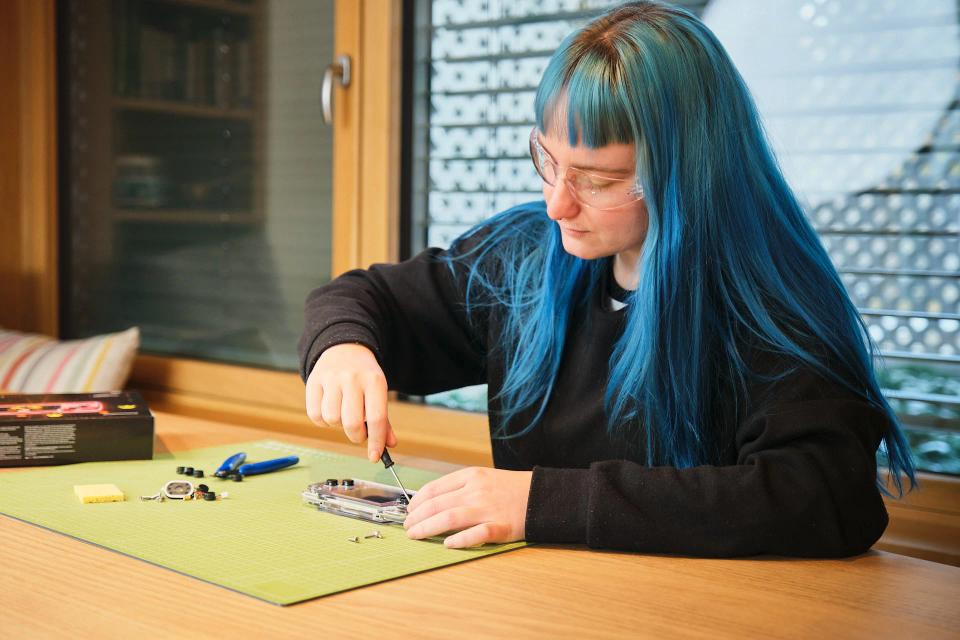 A woman using a screwdriver to assemble CircuitMess ByteBoi