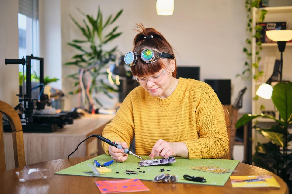 A woman using soldering tools to assemble CircuitMess Synthia on a Silicone Work Mat