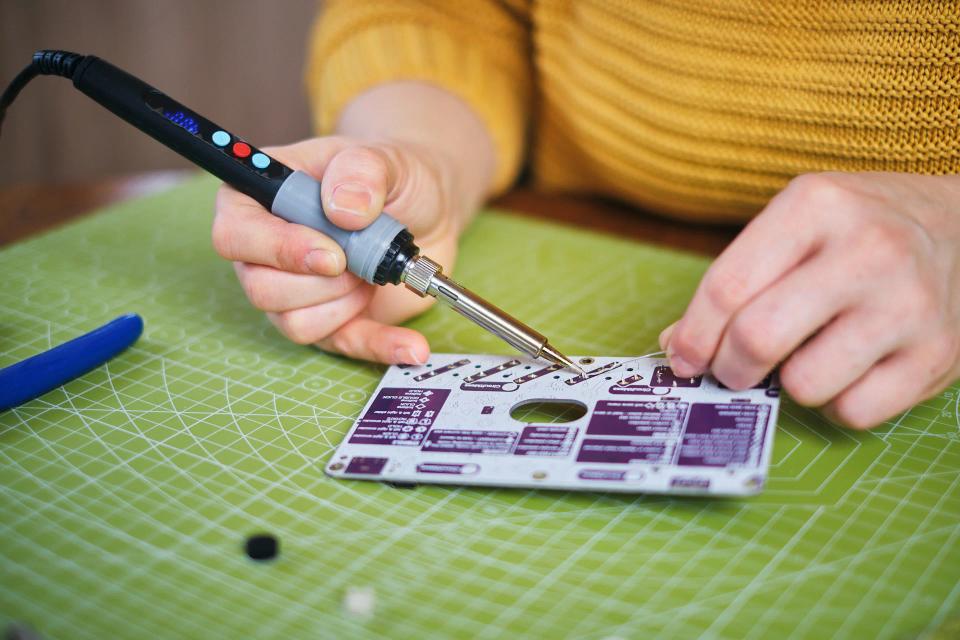 A woman using soldering tools to assemble CircuitMess Synthia on a Silicone Work Mat