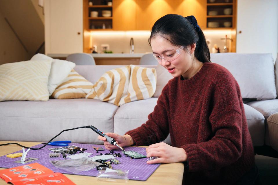 A woman using soldering tools to assemble CircuitMess Chatter