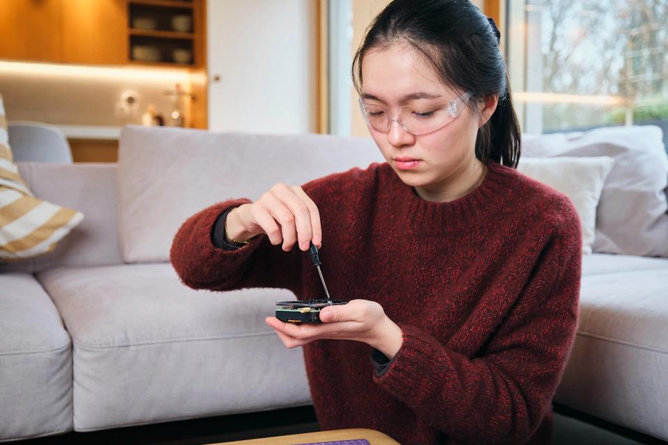 A woman using a screwdriver to assemble CircuitMess Chatter