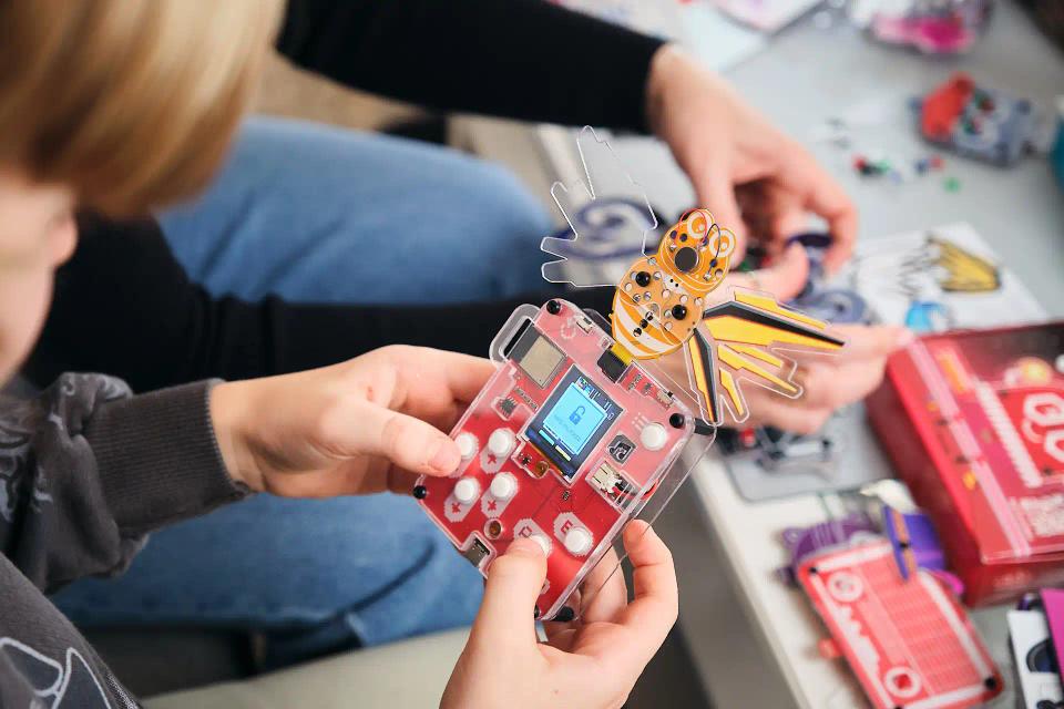 A boy playing CircuitMess Bit with a Mr. Bee game attached to it