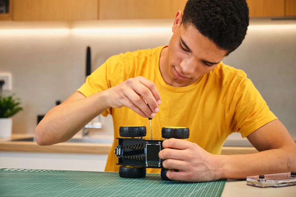 A man using a screwdriver to assemble CircuitMess Wheelson