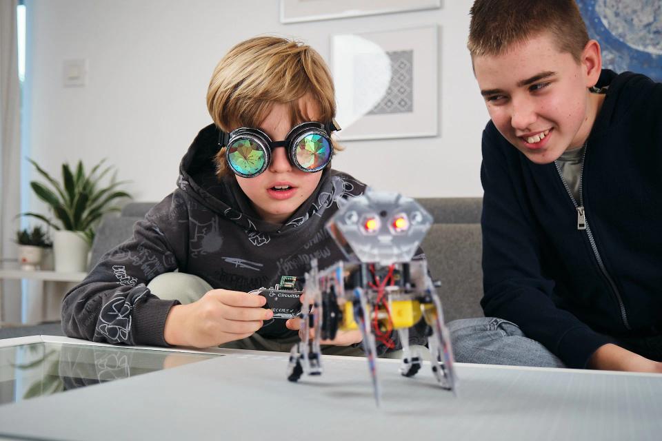 Two boys playing with CircuitMess Charlie and its controller