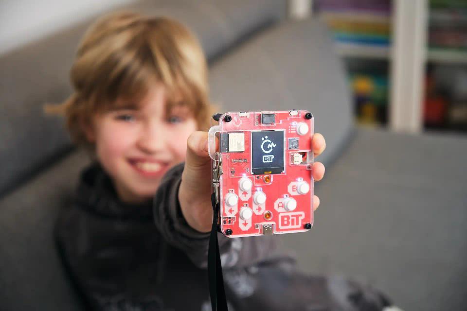 A boy holding CircuitMess Bit to the camera