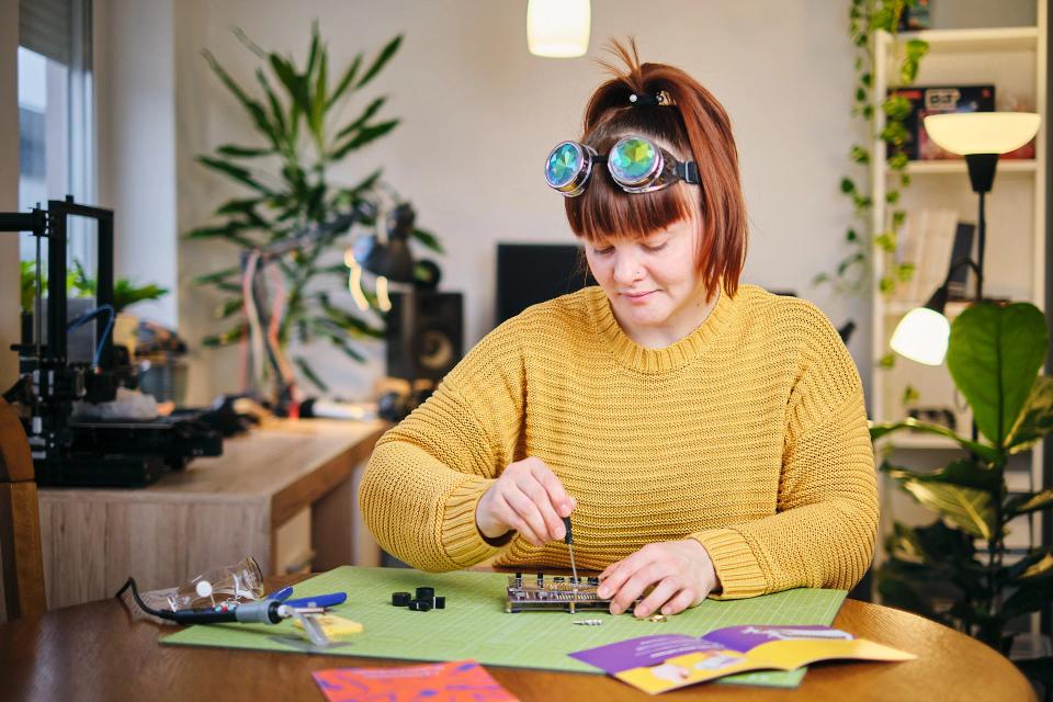 A woman using a screwdriver to assemble CircuitMess Synthia on a Silicone Work Mat