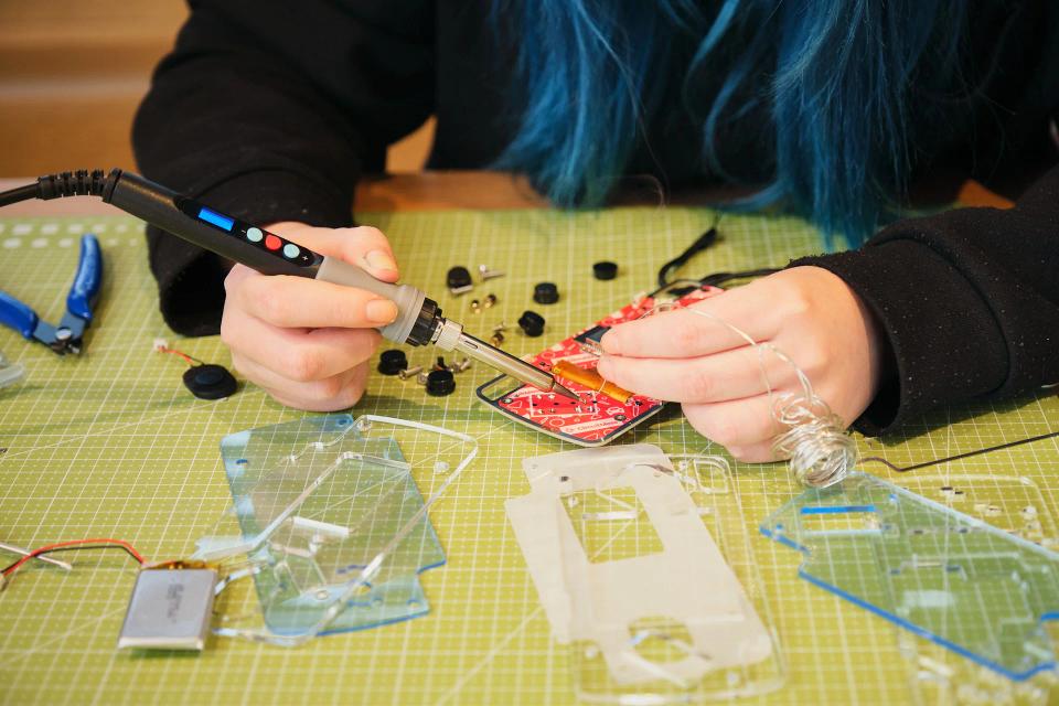 A person soldering the parts onto the CircuitMess ByteBoi PCB