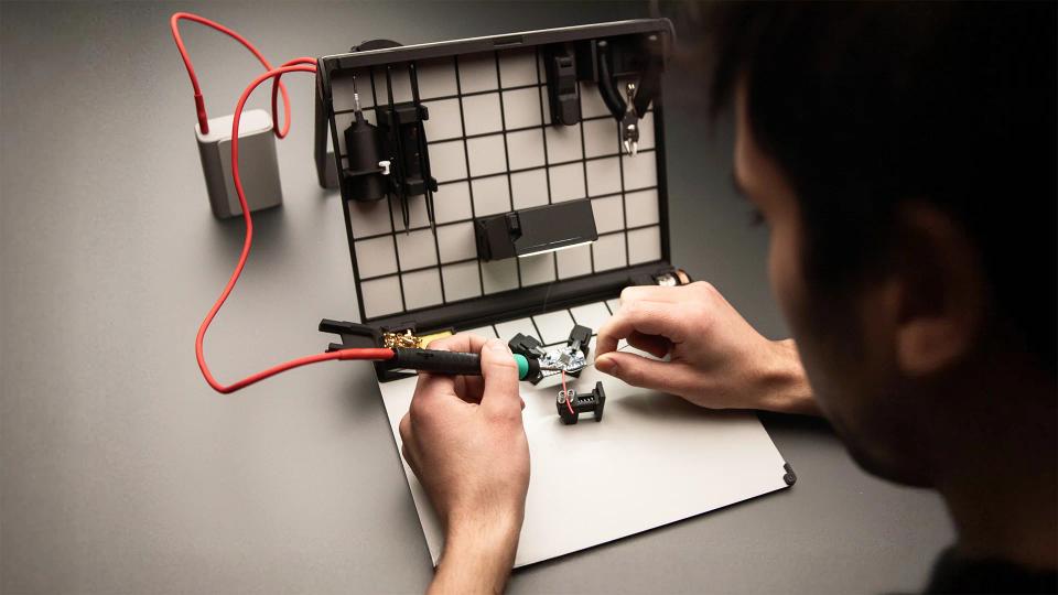A person soldering with SOLDR Deluxe soldering kit.