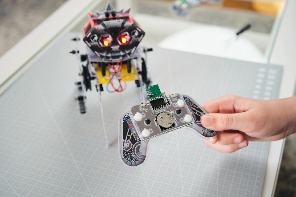 CircuitMess Charlie on a Silicone Work Mat with a person holding the controller