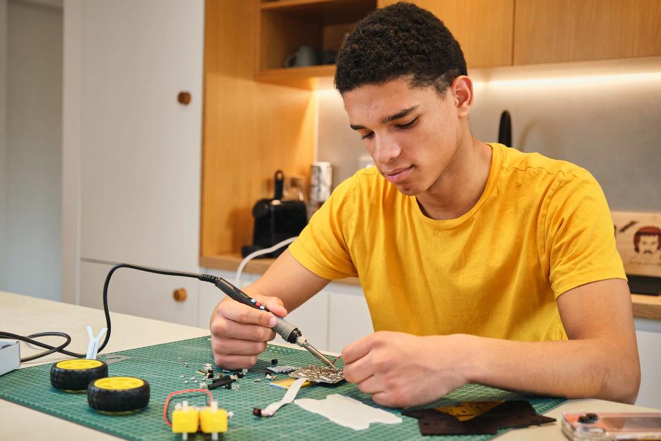 A man using soldering tools to assemble CircuitMess Wheelson