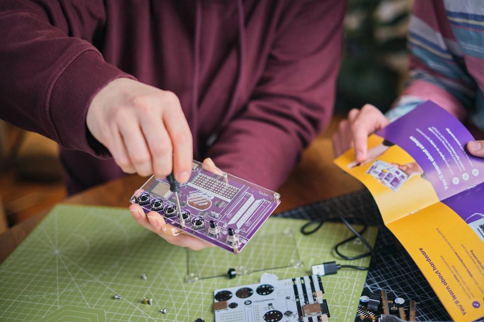 A group of people reading instructions and assembling CircuitMess Synthia
