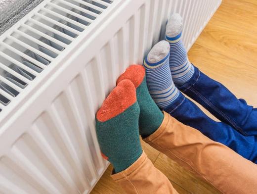 Two pairs of feet on a radiator
