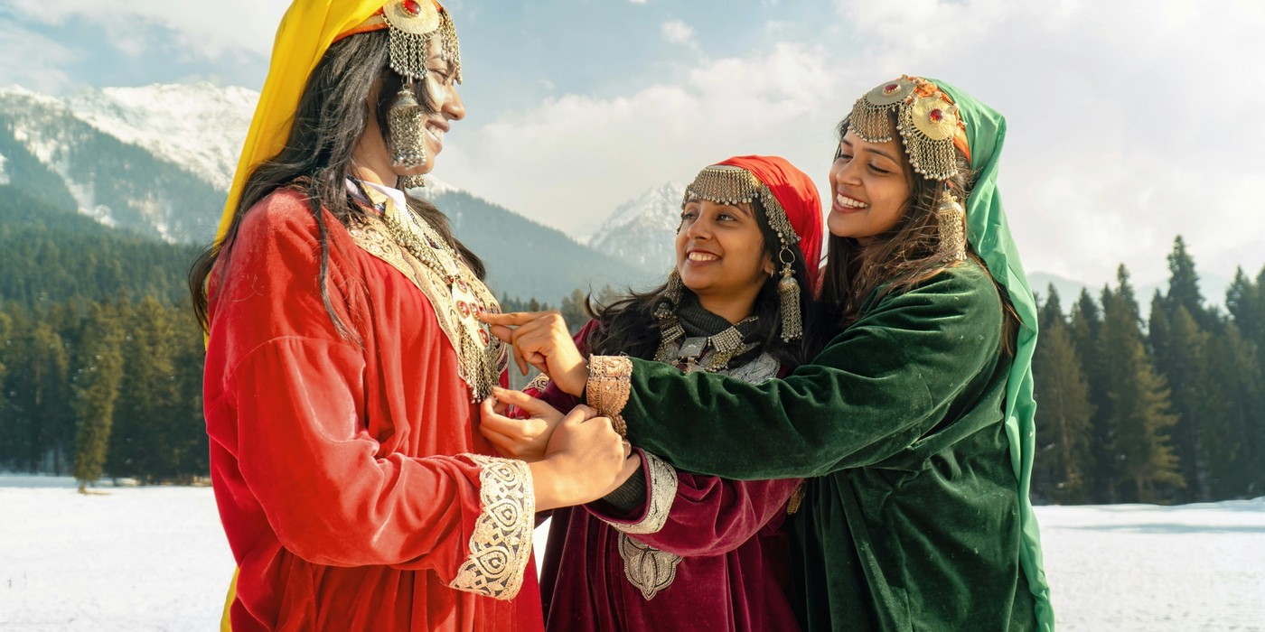 Family enjoying a Kashmir holiday in traditional Kashmiri attire with snow-covered mountains