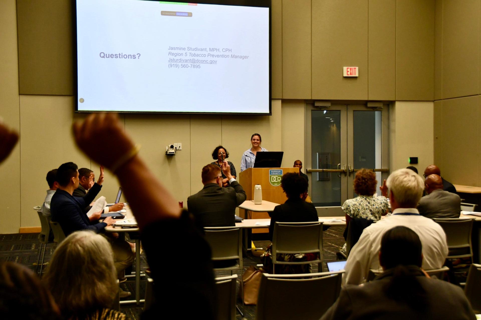 The Durham County Board of Health votes on a proposal while an audience member cheers.