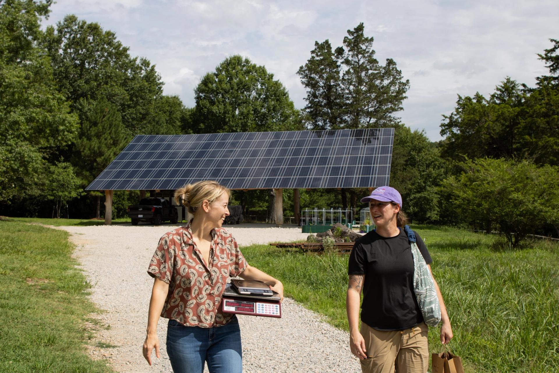 Two people talking as they walk away from a solar panel at Burkett Farm.