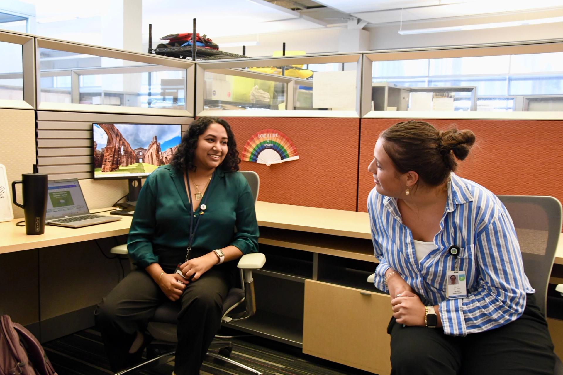 Neha Vaddepally (left) and Emma Llewelyn talk in their shared cubicle.
