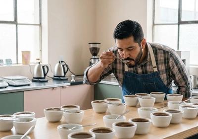 Sesión de catación de café con múltiples tazas dispuestas sobre una mesa de madera para evaluar notas de sabor