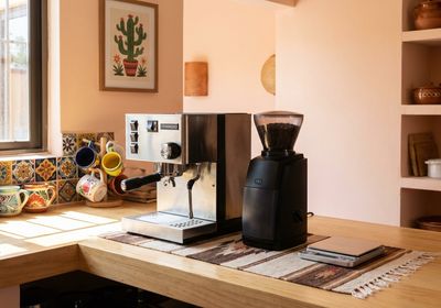 Setup de espresso casero con máquina de espresso semiautomática, molinillo de muelas, tamper, báscula y accesorios dispuestos en una encimera de cocina