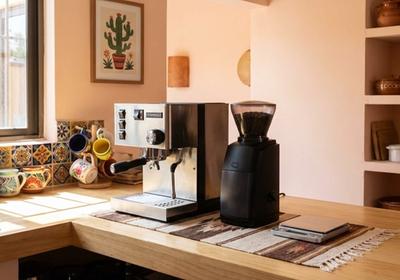 Installation espresso maison avec machine à espresso semi-automatique, moulin à meules, tasseur, balance et accessoires disposés sur un plan de travail de cuisine