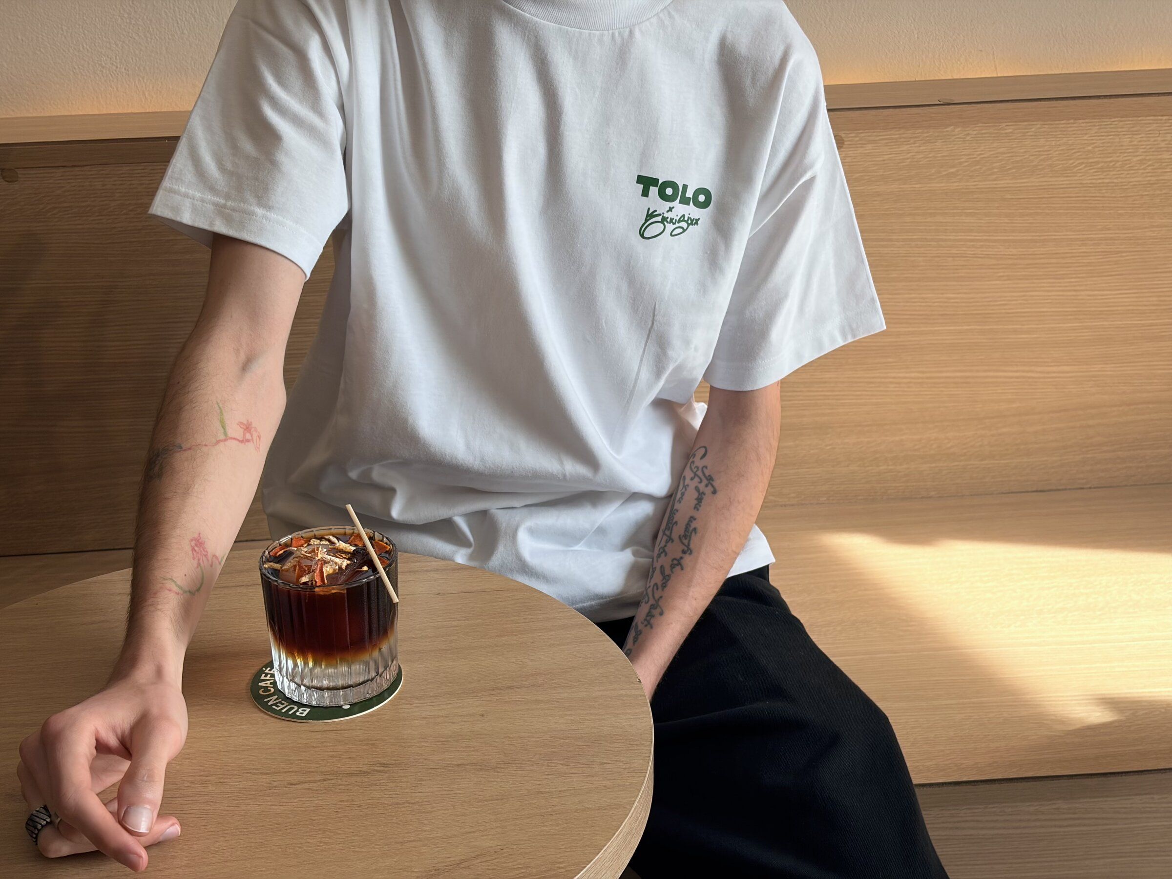 Detail vorne: TOLO × Kikki Sixx in Grün auf der Brust des weißen Shirts