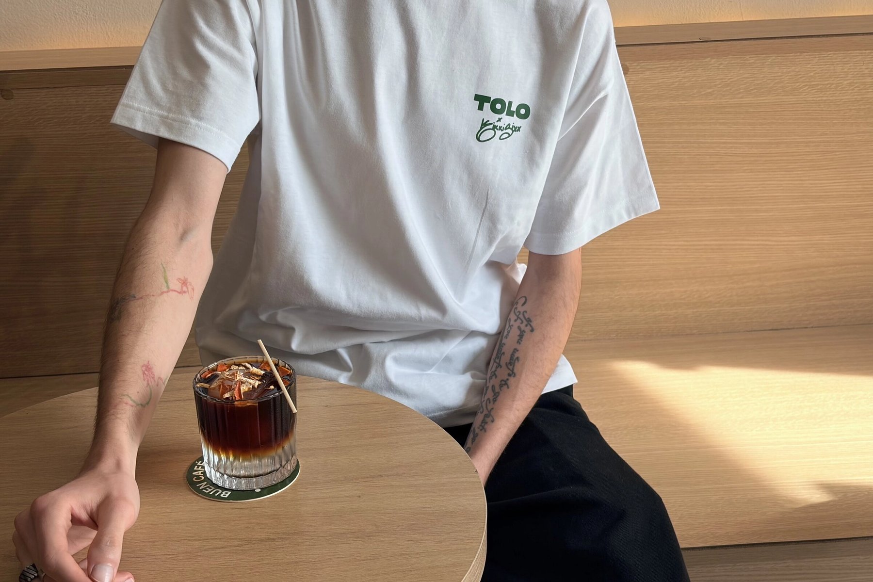 Detail vorne: TOLO × Kikki Sixx in Grün auf der Brust des weißen Shirts