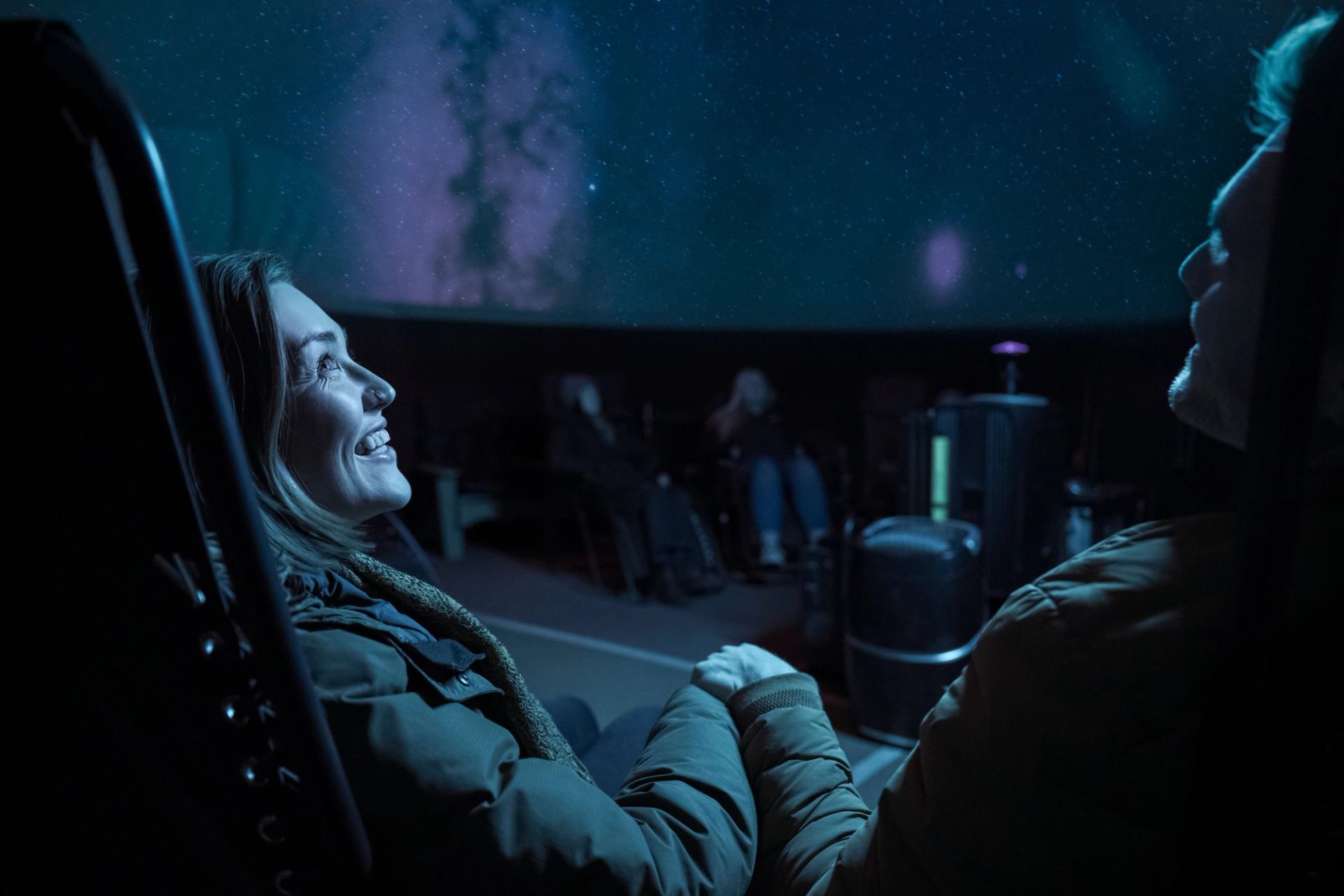 Young couple viewing projected sky in planetarium.