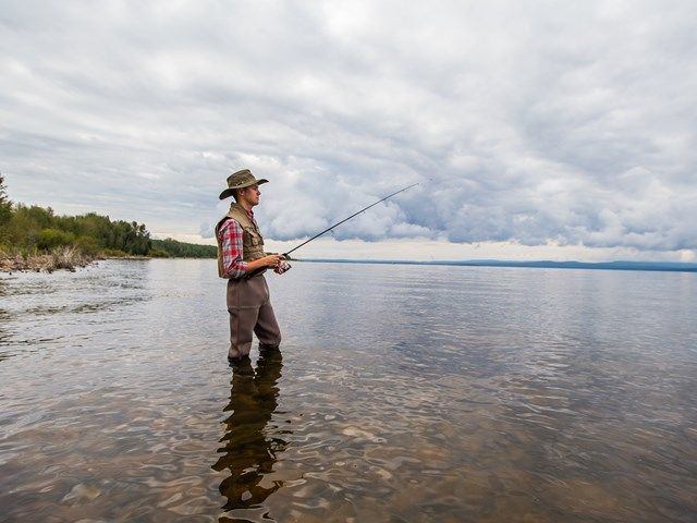 A young man fishes from the shore of Lesser Slave Lake.