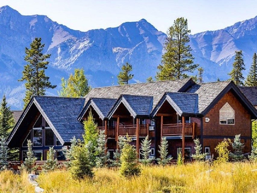 Lodge style accommodations with towering trees and mountains in the background.