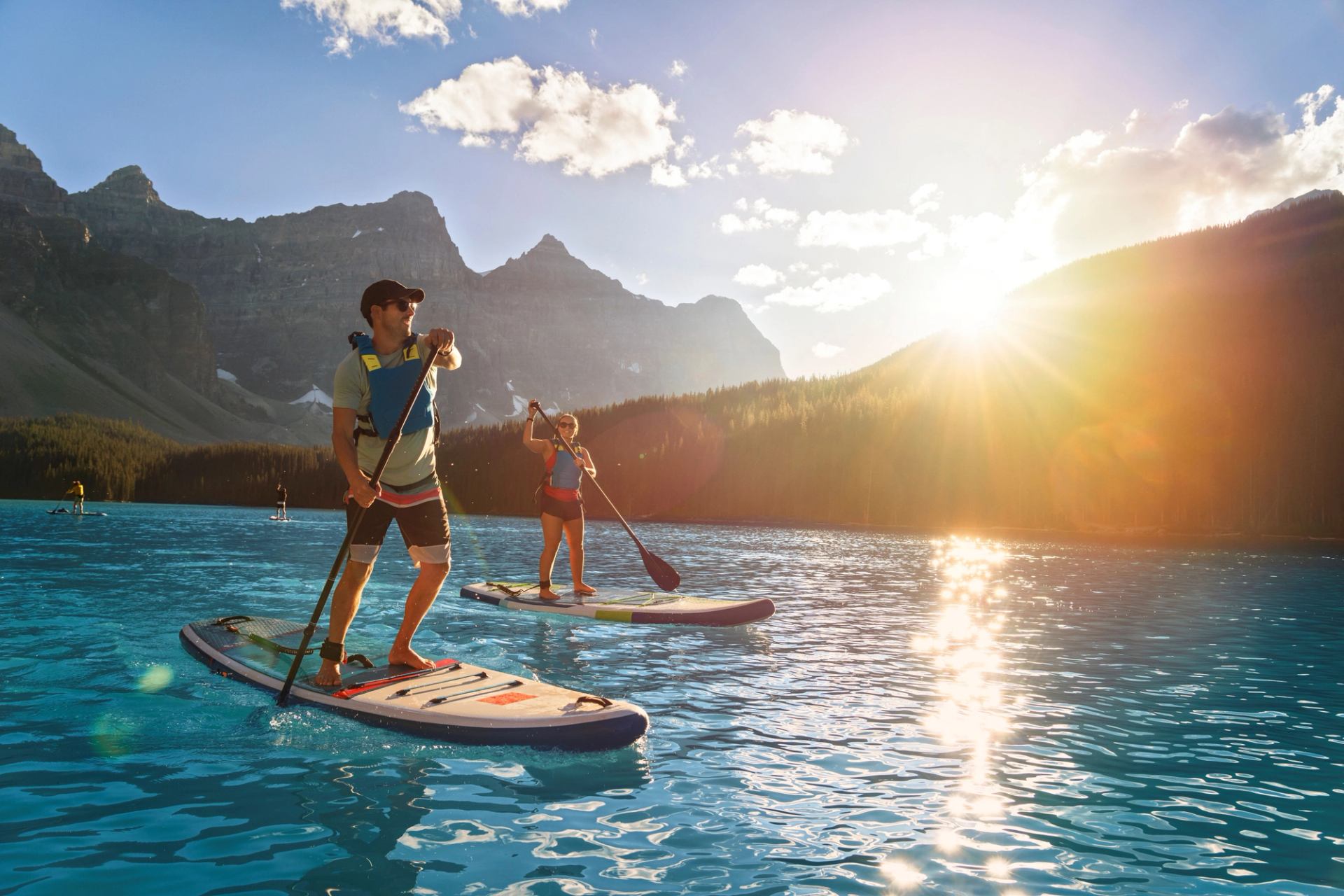 Couple paddleboarding on a sparkling Moraine Lake as the sun rises in Banff National Park.