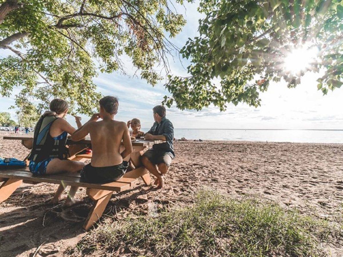 People sitting to a picnic table at the lake.