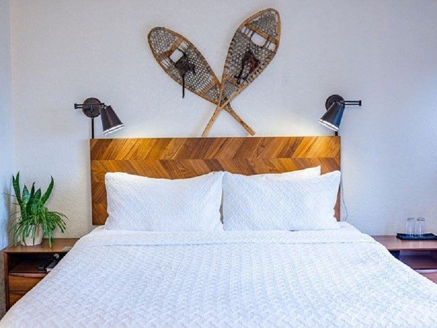 Traditional snowshoes are mounted above a freshly made bed with white linens.