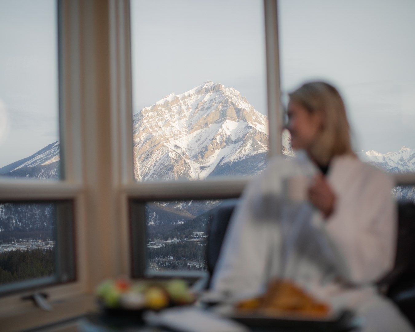 a woman drinking coffee and enjoying breakfast from her room at Rimrock Banff