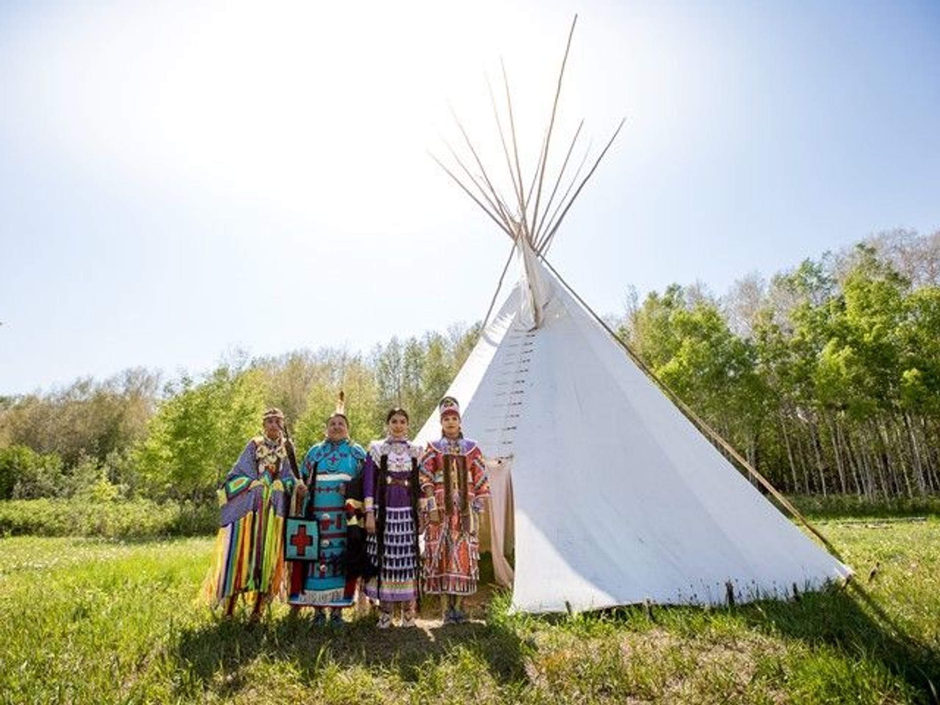 Siksika Blackfoot dancers standing in front of a tipi in Tipi Village.