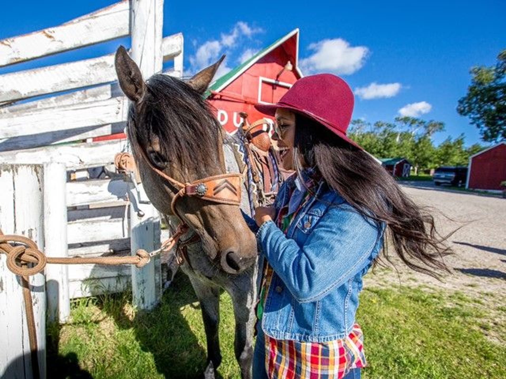 A woman pets a horse before horseback riding with Centre Peak High Country Adventures in the Crowsnest Pass.